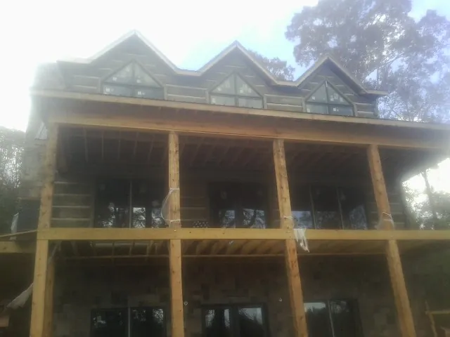 Dormers and porch framing on a large log home under construction — Roof Coating work by our crew in Roaring Spring