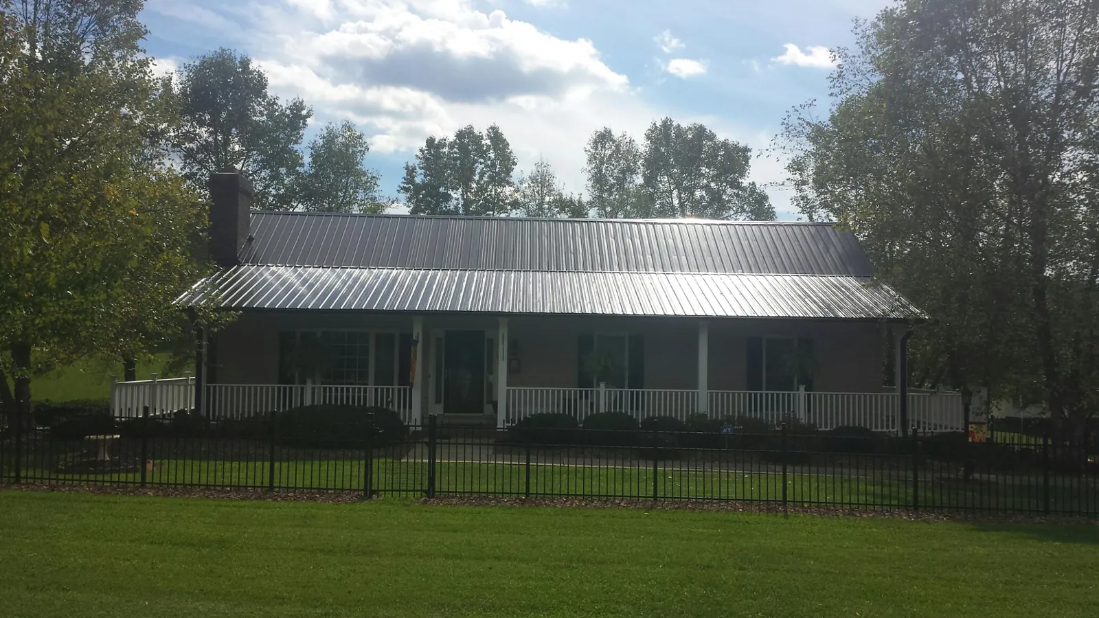 Gray metal roof on a brick ranch with a full width front porch — Gutter Guard Installation work by our crew in Roaring Spring