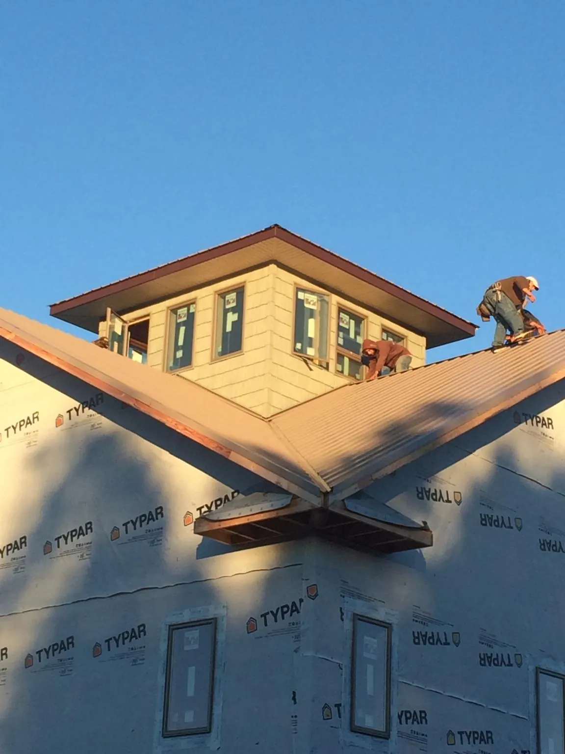 Roofers working around a rooftop cupola on a new metal roof at sunset — Roof Waterproofing in Roaring Spring by Roofing Brothers